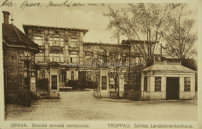 127903_m.jpg - Hlavní brána nemocnice na pohlednici z 20.let 20.století. Budka vpravo je tramvajová zastavka.